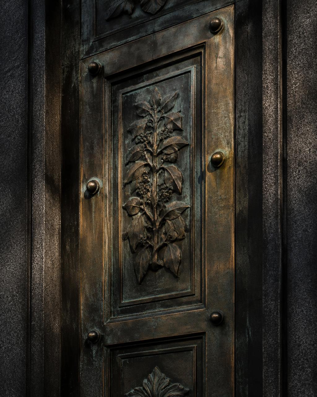 Aged bronze door panel set in dark stone